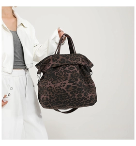 Detail of large leopard print canvas tote bag with dual handles and crossbody strap