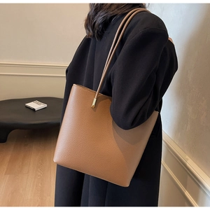 Close-up of brown PU leather tote bag showing lychee grain texture and gold metal accents