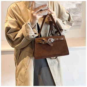 Detailed view of dark brown faux suede bag featuring a vintage buckle and sturdy handle