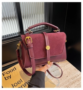 Close-up of wine red suede handbag with vintage gold hardware and elegant top handle