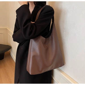 Close-up of deep brown lychee grain leather texture on a minimalist tote bag for women