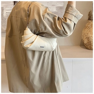 Detail view of cream ruched dumpling bag with lychee texture leather and chain strap