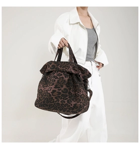 Detailed macro view showing leopard print canvas texture and adjustable strap of the tote bag