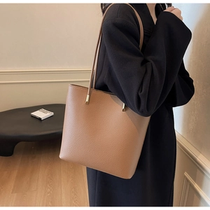Close-up of tan PU leather tote bag showing fine pebble texture and gold buckles