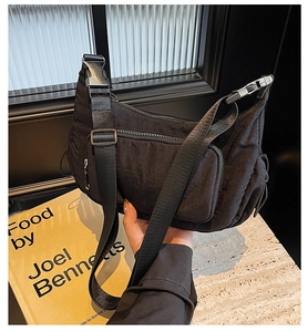 Dettaglio borsa a tracolla in nylon nero con tracolla regolabile e tasca frontale con zip
