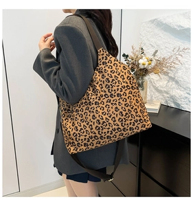 Close-up of leopard print tote bag featuring a wide black shoulder strap and canvas texture