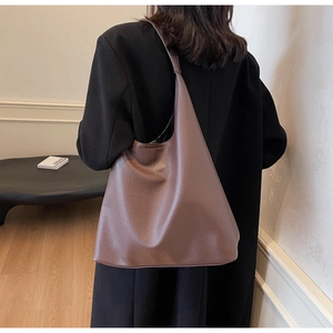 Detailed side view of the brown lychee pattern leather hobo bag worn by a model