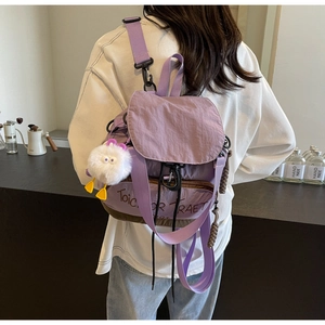 Détail d'un sac à dos en nylon violet avec broderie et pendentif peluche blanche