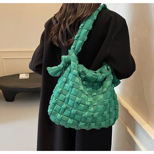 Détail du sac à bandoulière tressé vert matelassé montrant la texture et le nœud de sangle