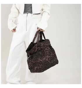 Close-up of leopard print canvas tote bag featuring metal D-rings and durable handles