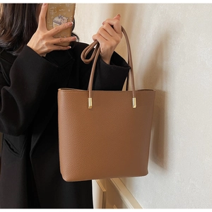Detail view of large caramel brown tote bag with premium lychee grain texture and gold hardware