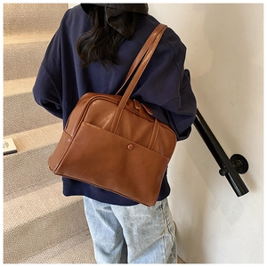 Close-up of brown PU leather tote bag featuring a practical side pocket with round buckle