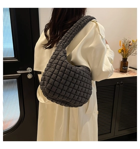 Detail view of dark grey quilted shoulder bag with bubble texture on a model