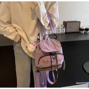 Détail du sac à dos en toile violette avec motif graphique et breloque peluche monstre