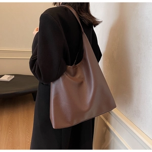 Detailed view of brown lychee-textured leather tote bag on model in a minimalist setting