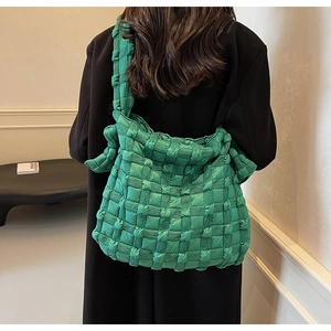 Détail du sac à bandoulière matelassé vert émeraude avec sangle large sur un mannequin