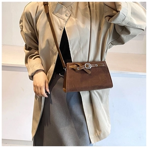 Detail of a vintage dark brown matte crossbody bag with silver buckle and fine stitching