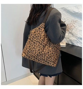 Close-up of leopard print tote bag with brown wide strap and metal buckle detail