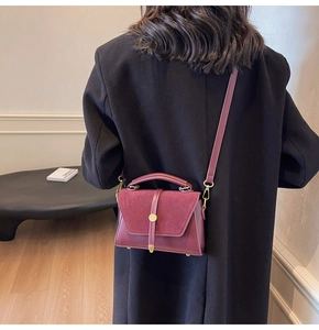 Detail view of burgundy suede and smooth leather crossbody bag with gold metal buckle