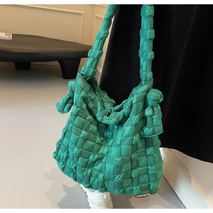 Détail du sac cabas vert tressé avec nœud latéral sur une robe noire élégante