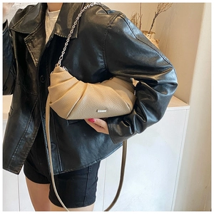 Detail of beige croissant shoulder bag in lychee leather with chain strap on a model
