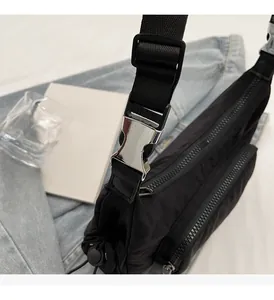 Dettaglio borsa a tracolla in nylon nero con fibbia in metallo argento e tasca a zip