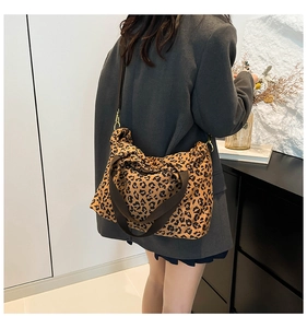 Detail of large leopard print tote bag with wide brown strap shown on shoulder