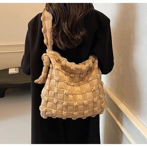 Détail du sac cabas beige matelassé avec bandoulière à nœud porté par le mannequin