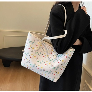 Détail du sac cabas blanc en cuir PU avec motifs floraux colorés et plaque logo en métal