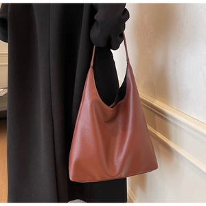 Detail of caramel leather hobo bag with pebble grain texture on black coat