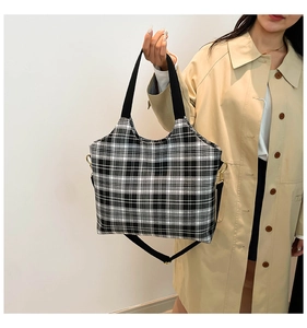 Close-up of black and white checkered canvas tote bag with adjustable shoulder strap