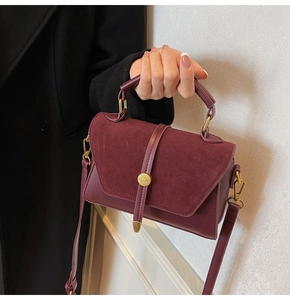 Detailed close-up of dark wine red suede and leather mini square handbag with gold hardware