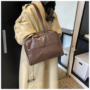 Detail of deep brown PU leather tote bag with pocket and zipper on female model