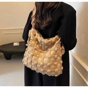 Détail du sac à bandoulière beige matelassé avec texture 3D et design à nœuds