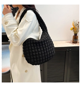 Detail of a black quilted bubble texture fabric hobo shoulder bag with a puffy nylon strap