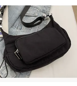 Dettaglio borsa a tracolla in tessuto nero con cerniera in metallo e tracolla in nylon