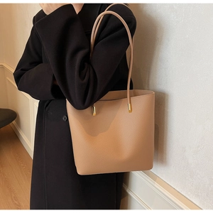 Detail view of camel PU leather tote bag with fine litchi grain and gold metal hardware