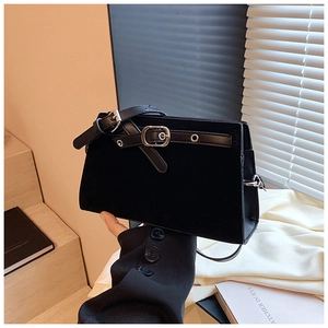 Handheld view of black suede shoulder bag with adjustable silver buckle strap detail