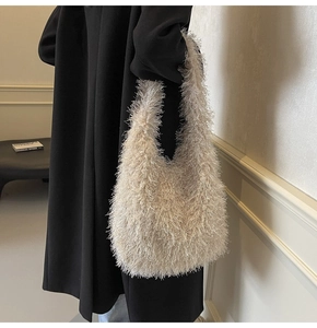 Détail de la texture d'un sac à bandoulière beige en peluche sur un long manteau noir