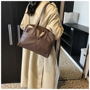 Detail of a dark brown PU leather tote bag with a metal button pocket and dual zipper system