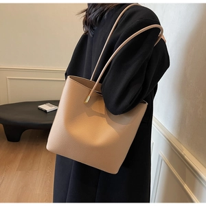 Detail of beige lychee pattern PU leather tote bag with elegant gold metal hardware