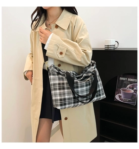 Fashionable large capacity black and white checkered tote bag worn with a beige trench coat