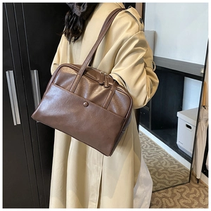 Close-up of vintage brown PU leather shoulder bag featuring a front pocket with buckle detail