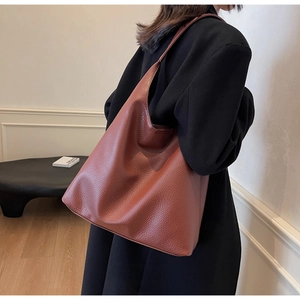Detail of caramel brown PU leather tote bag showing lychee grain texture and minimalist design