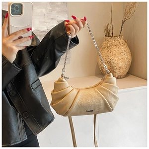 Close-up of litchi-textured cream crescent bag featuring silver chain and metal logo