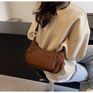 Dettaglio di una borsa a tracolla in nylon marrone scuro con coulisse e fibbie argento