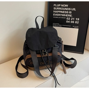 Sac à dos chic noir et marron avec broderie orange sur une table blanche moderne