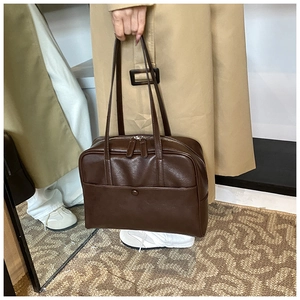 Close-up of retro brown PU leather shoulder bag with fine texture and metal zipper detail