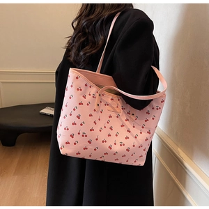 Sac fourre-tout en cuir PU rose avec imprimé cerises et bandoulière sur un manteau noir