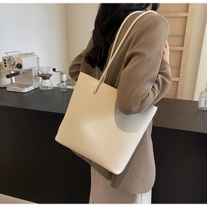 Detail of a minimalist cream PU leather tote bag showing grainy texture and long straps